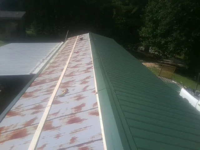 Old rusted panels beside newly installed green metal roofing — Wind Damage Roof Repair by Roofing Brothers in Cedar Park