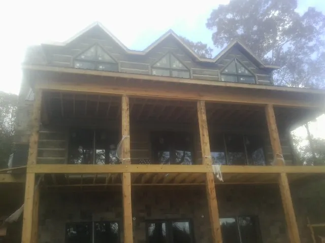 Dormers and porch framing on a large log home under construction — Roof Coating work by our crew in Cedar Park