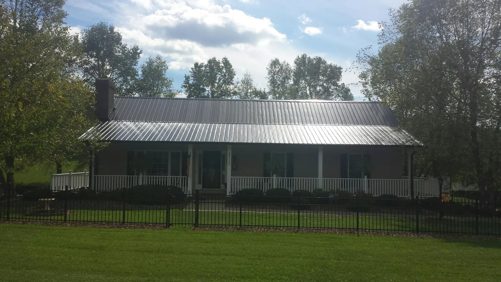 Gray metal roof on a brick ranch with a full width front porch — Gutter Guard Installation work by our crew in Cedar Park