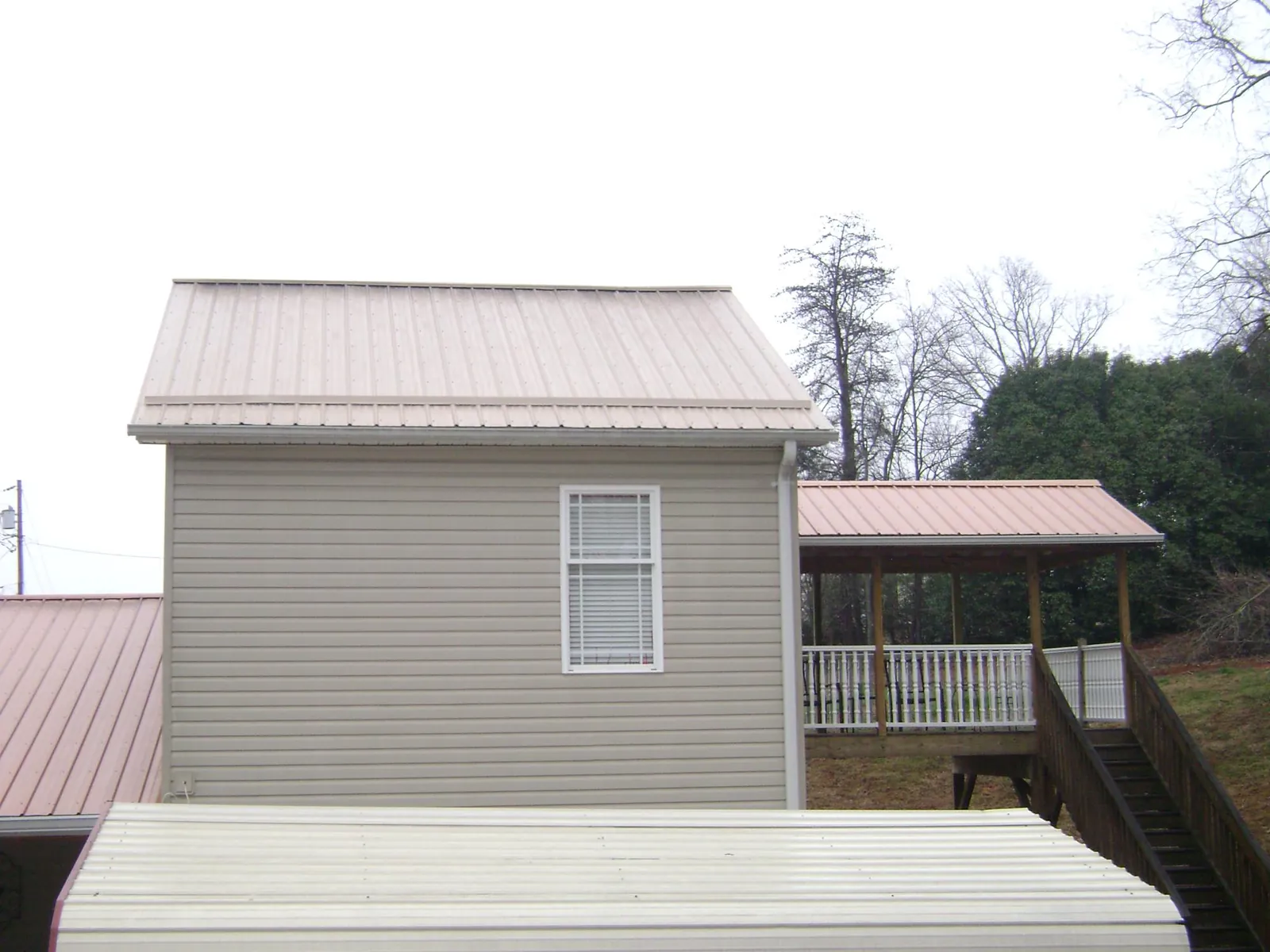 Tan metal roofs on a two story addition and attached porch, from a Roof Replacement job in Cedar Park