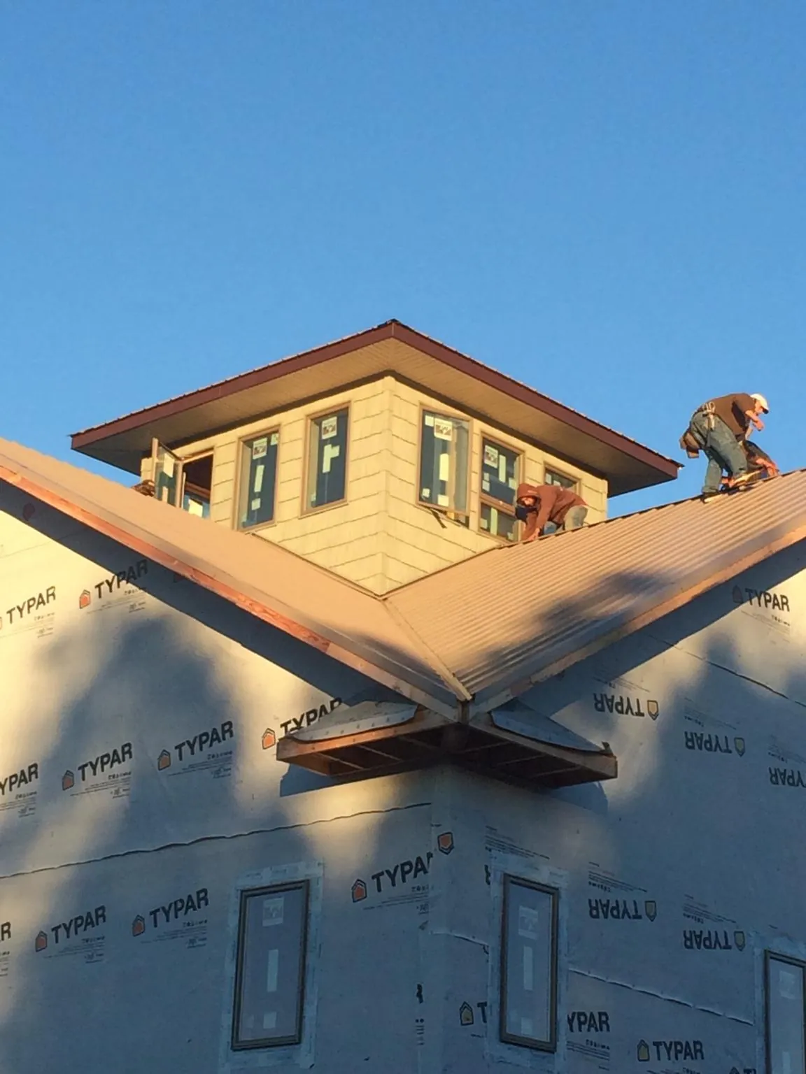 Roofers working around a rooftop cupola on a new metal roof at sunset — Roof Waterproofing in Cedar Park by Roofing Brothers
